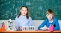 School laboratory. Girl and boy smart students conduct school experiment. Describe chemical reaction notepad. School