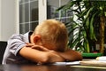 The schoolboy fell asleep at the desk doing homework. Tired boy sleeping on the table Royalty Free Stock Photo
