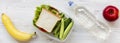 School lunch box with sandwich, fruits and bottle of water on white wooden background, flat lay. From above, overhead
