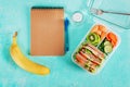 School lunch box with sandwich, vegetables, water, and fruits on table. Royalty Free Stock Photo