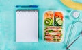 School lunch box with sandwich, vegetables, water, and fruits on table. Royalty Free Stock Photo