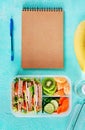 School lunch box with sandwich, vegetables, water, and fruits on table. Royalty Free Stock Photo