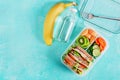 School lunch box with sandwich, vegetables, water, and fruits on table. Royalty Free Stock Photo