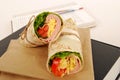 School lunch: ham and cheese wrap sandwich with lunch bag on the book Royalty Free Stock Photo