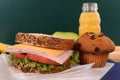 School lunch sandwich, cake and drink on classroom desk with blackboard Royalty Free Stock Photo