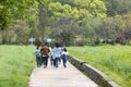 7 4 2023 school male and female teachers and primary boy and girl walk on countryside concrete road among rapeseed farm field,