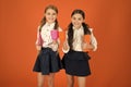 School mates relaxing with drink. Enjoy being pupil. Girls kids school uniform orange background. Schoolgirl hold book