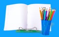 School notebook and colored pencils in a blue glass on a white background. Royalty Free Stock Photo