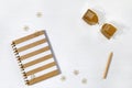 School notebook on spring, wooden pencil, hourglass and gold metal figured clips on white work space