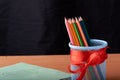 School and office supplies on classroom table in front of blackboard. View with copy space Royalty Free Stock Photo