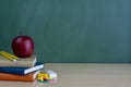 School and office supplies on classroom table in front of blackboard. Royalty Free Stock Photo