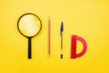 School and office supplies flat lay on yellow background top view. Back to school. Magnifier, protractor, pencil, pen.