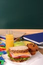 School packed lunch on classroom desk with blackboard, copy space, vertical Royalty Free Stock Photo