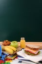 School packed lunch sandwich, apple, drink on classroom desk with blackboard copy space, vertical Royalty Free Stock Photo