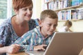 School Pupil With Teacher Using Laptop Computer In Classroom