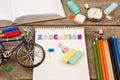 inscription of & x22;education& x22;, bicycle model, stopwatch, book, notepad and other stationery on brown wooden table