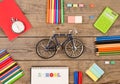 inscription of & x22;school& x22;, bicycle model, stopwatch, calculator, notepads and other stationery on brown wooden table Royalty Free Stock Photo