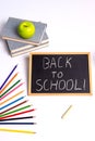 ÃÂ blackboard with the inscription back to school, a green apple, books and colored pencils on a white Royalty Free Stock Photo