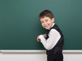 School student boy posing at the clean blackboard, grimacing and emotions, dressed in a black suit, education concept, studio Royalty Free Stock Photo