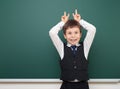 School student boy posing at the clean blackboard, grimacing and emotions, dressed in a black suit, education concept, studio Royalty Free Stock Photo