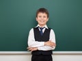 School student boy posing at the clean blackboard, grimacing and emotions, dressed in a black suit, education concept, studio Royalty Free Stock Photo