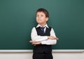 School student boy posing at the clean blackboard, grimacing and emotions, dressed in a black suit, education concept, studio Royalty Free Stock Photo