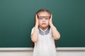 School student girl posing at the clean blackboard, grimacing and emotions, dressed in a black suit, education concept, studio pho Royalty Free Stock Photo