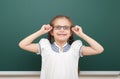 School student girl posing at the clean blackboard, grimacing and emotions, dressed in a black suit, education concept, studio pho Royalty Free Stock Photo