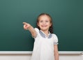 School student girl posing at the clean blackboard, grimacing and emotions, dressed in a black suit, education concept, studio pho Royalty Free Stock Photo