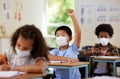 School student raising hand to volunteer, participate and answer question at class lesson in covid pandemic. Curious Royalty Free Stock Photo