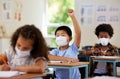 School student raising hand to volunteer, participate and answer question at class lesson in covid pandemic. Curious Royalty Free Stock Photo