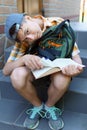 school student, a teenage boy is sitting on the steps near the building, reading a book, a bright summer day, back to school and