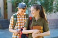 school students, a teenage boy and a girl are walking down the street, having fun, talking, reading books, a bright summer day in Royalty Free Stock Photo
