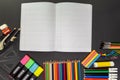 School supplies on black board background, with open notebook. Education, back to school concept with copy space Royalty Free Stock Photo
