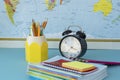 school supplies and black round clock on map background. Royalty Free Stock Photo