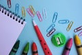 School supplies on a blue background. Back to school concept. Top view, copy space. Open paper notebook, pen, sharpener, crayons Royalty Free Stock Photo