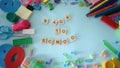 School supplies on the blue background. Woman hand put a wooden words with text back to school.