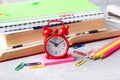 School supplies, clock book notebooks pencils on grey background with copy space