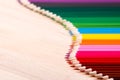 School supplies colored pencils forming a wave, on a wooden background Royalty Free Stock Photo