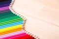 School supplies colored pencils forming a wave, on a wooden background Royalty Free Stock Photo