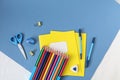 School supplies-colored pencils, notebooks, pens, scissors-on a blue background, close-up, top view, place for writing