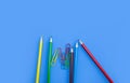 School supplies concepts, Multi-colored pencils and clips on blue background Royalty Free Stock Photo