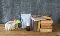 School supplies and COVID 19 prevention items on classroom desk with books,eyeglasses,pens on chalkboard background Royalty Free Stock Photo