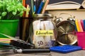 School supplies and glass jar with money for education on wooden table