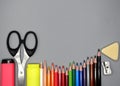 School supplies  colored pencils  pencil sharpener  eraser  markers and scissors at the bottom  gray background. Royalty Free Stock Photo