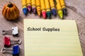 School Supplies List concept on notebook and wooden board