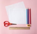 School supplies: multicolored wooden pencils, white sheets of school notebook in a cell, ruler, scissors, sharpener on pink backgr Royalty Free Stock Photo