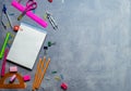 School supplies for school: notepad, pencils, pink ruler, compasses scattered on a gray table. Top view.