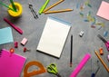 School supplies for school: notepad, pencils, pink ruler, compasses scattered on a gray table. Top view.