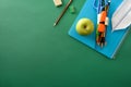 School supplies paper plane and apple on green background top Royalty Free Stock Photo